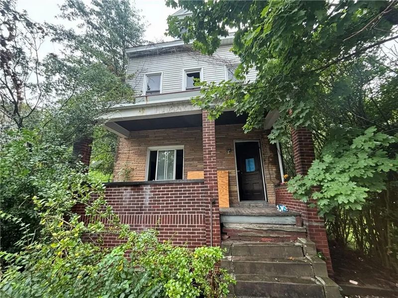 Brick house with a deep front porch and an overgrown yard, Pittsburgh, Pennsylvania